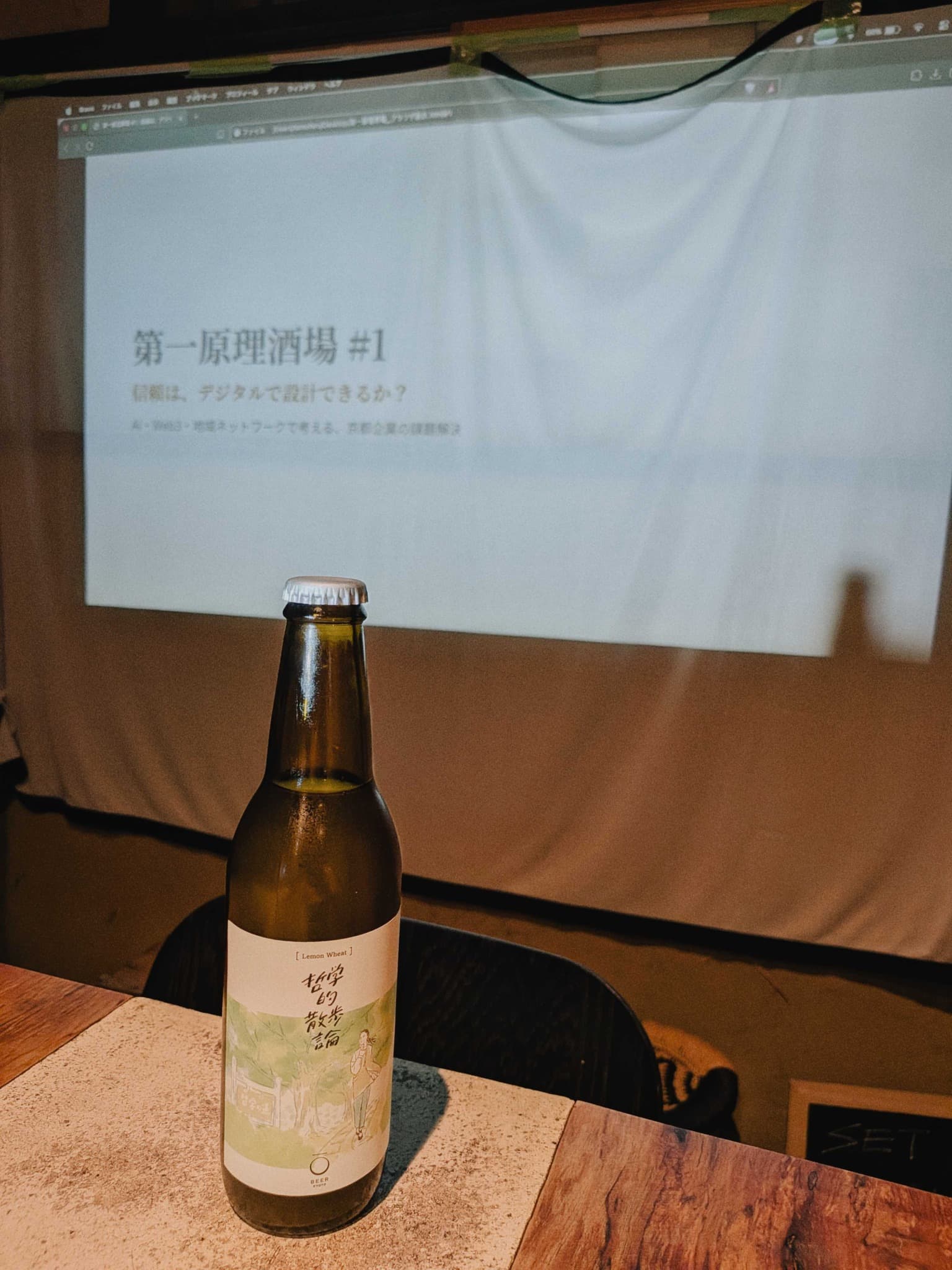 「第一原理酒場 #1」と投影されたスクリーン前のクラフトビール